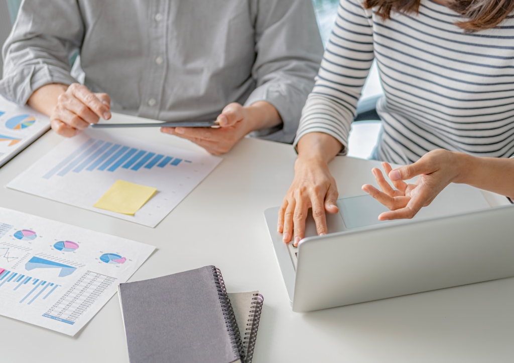 A stock photo of two people working at a laptop and consulting some paperwork